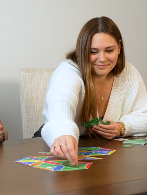 Close-up of a woman thoughtfully playing Trigahex, a simple yet strategic family card game that’s easy to learn and perfect for all ages on game night.