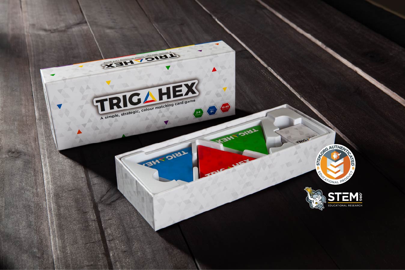 TRIGAHEX game box and components on a wooden surface with a STEM certification logo.