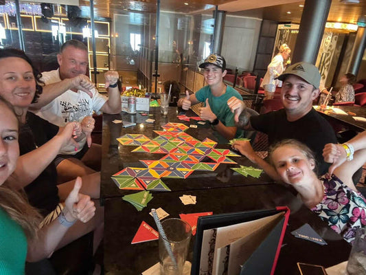 A family of all ages sitting around a table, smiling and enjoying a game of Trigahex together.