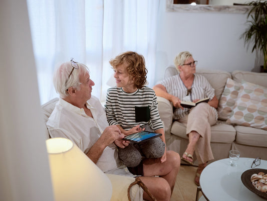 Two grandparents sitting on a couch with their grandson holding a tablet in a living room.