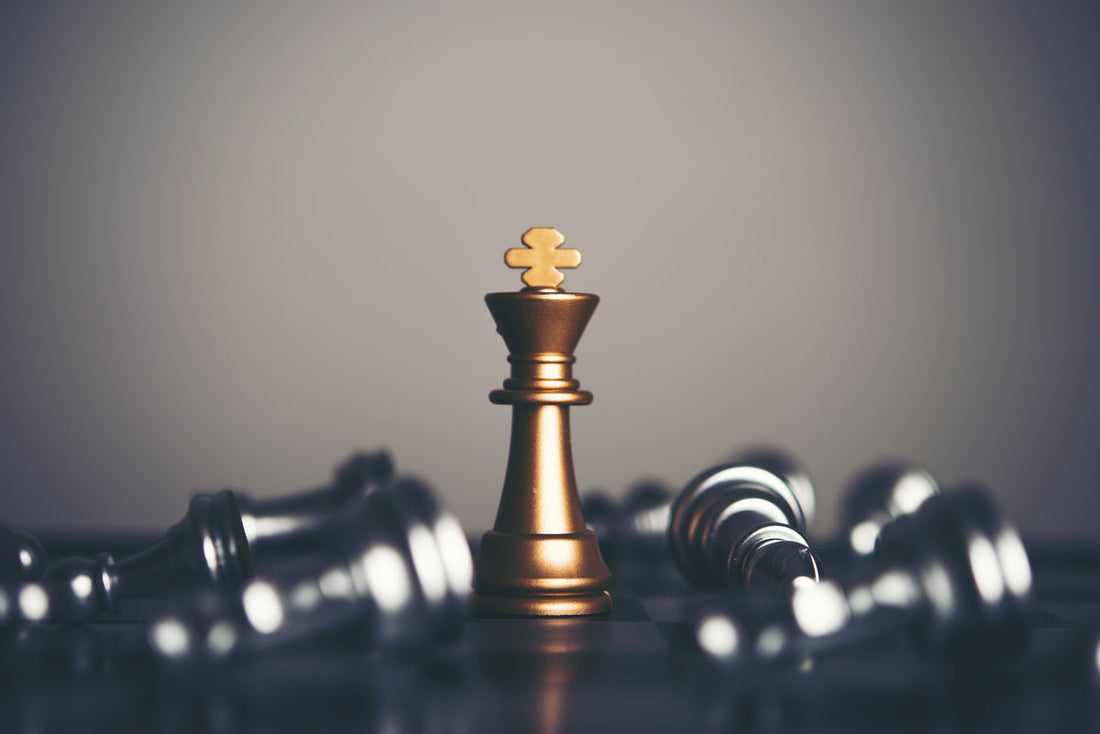 A golden chess king standing upright on a chessboard, surrounded by fallen silver pawns, symbolizing victory and strategic mastery.