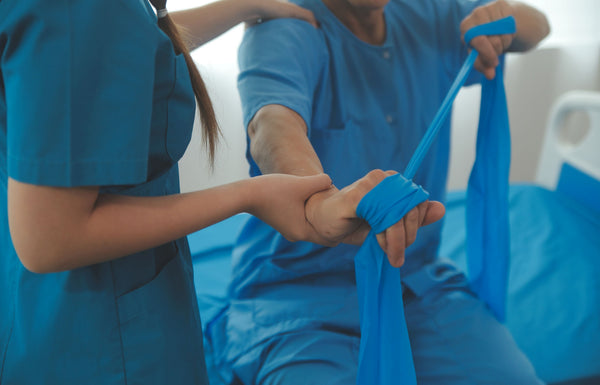 Physiotherapist assisting a patient with resistance band exercise in a clinical setting